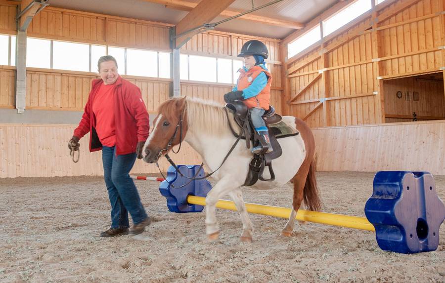 Vertrauen, Respekt und ein spielerischer Umgang mit den Pferden stehen in der Reithalle f├╝r Kinder ab drei Jahren im Vordergrund. Foto: djd/Familotel Landhaus zur Ohe 